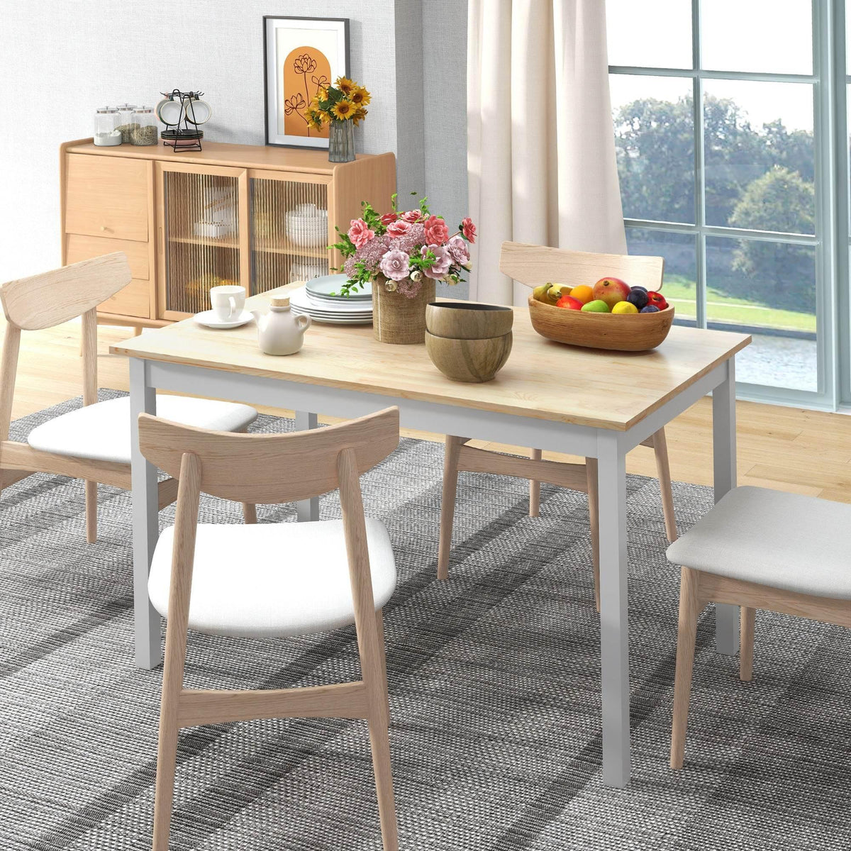 Light pine dining table with white base and four wooden chairs in a bright room
