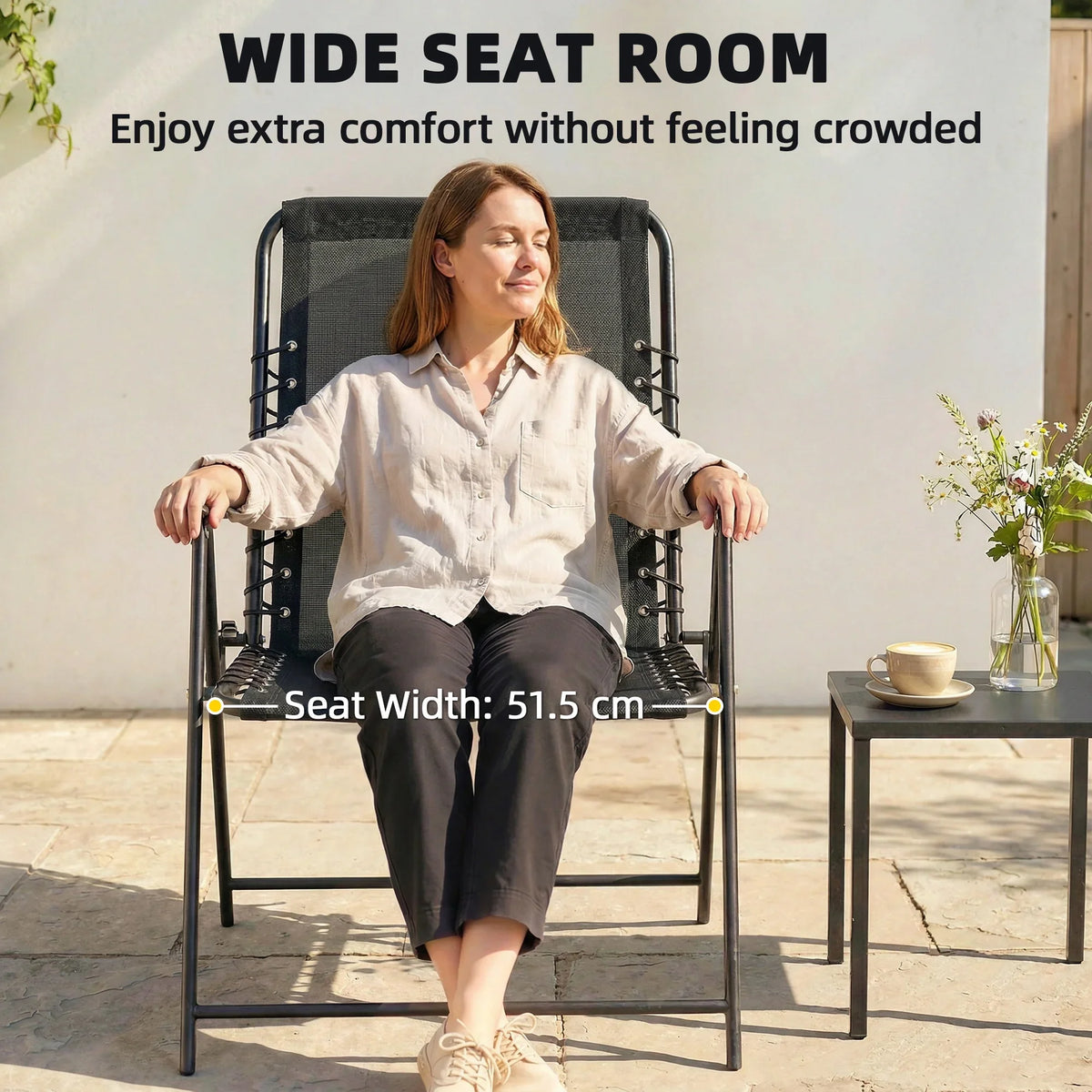 Black folding patio chair with high back and wide seat, person relaxing outdoors