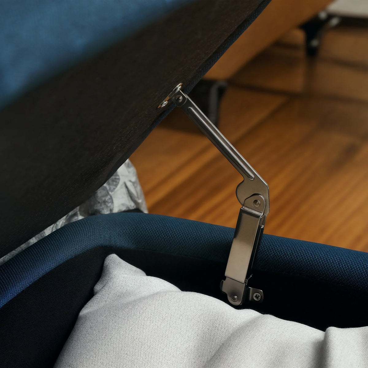 Dark blue storage ottoman hinge with metal support strut and lifted lid
