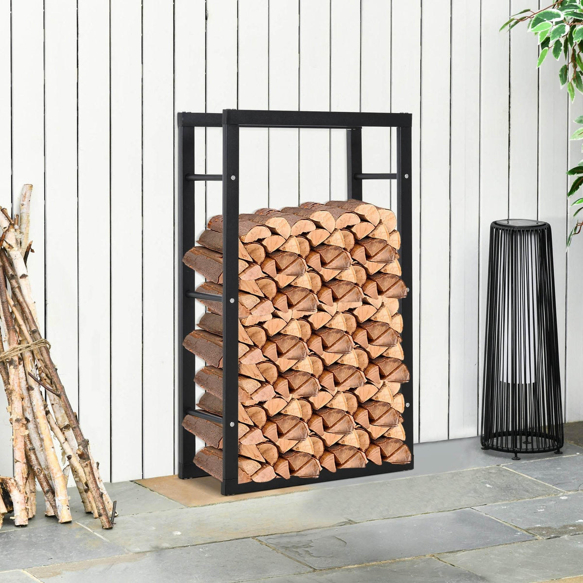 Tall black metal log holder with stacked firewood inside, slatted side frame