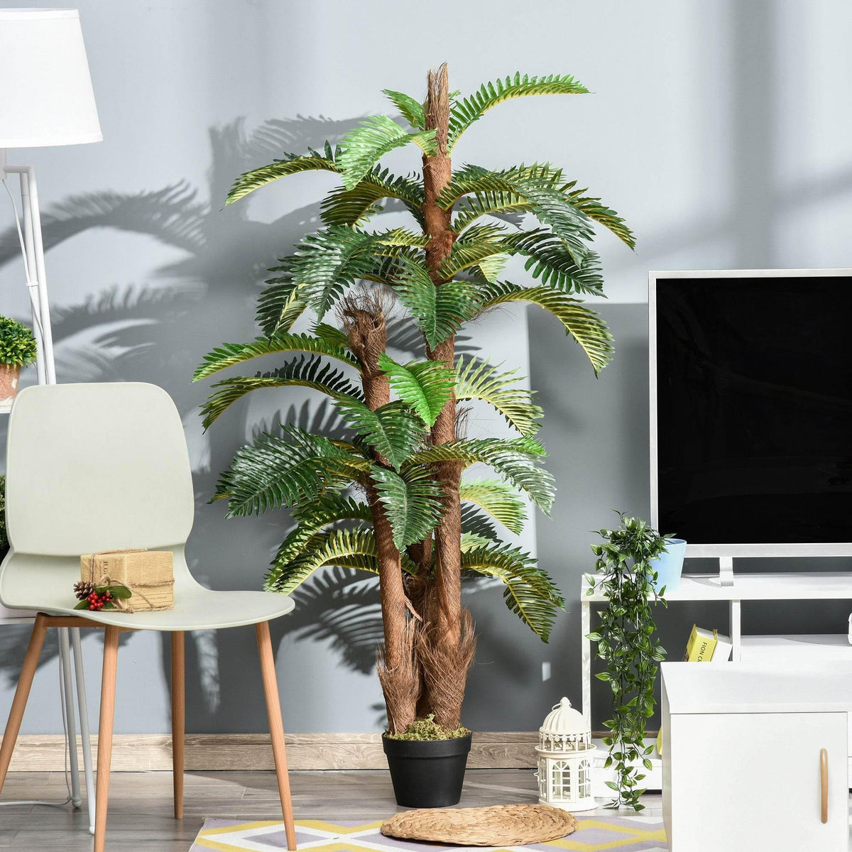 Artificial tropical palm plant in black pot with green fronds and brown trunk