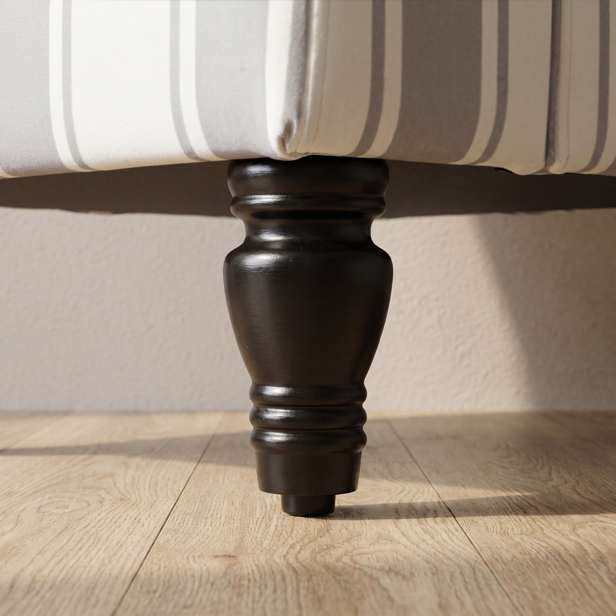 Dark turned wooden armchair leg with rounded base on light floor