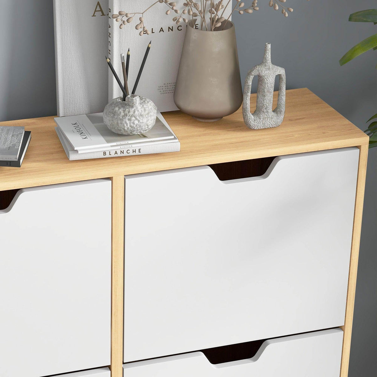 Close-up of natural wood shoe cabinet front with white flip drawer and storage top