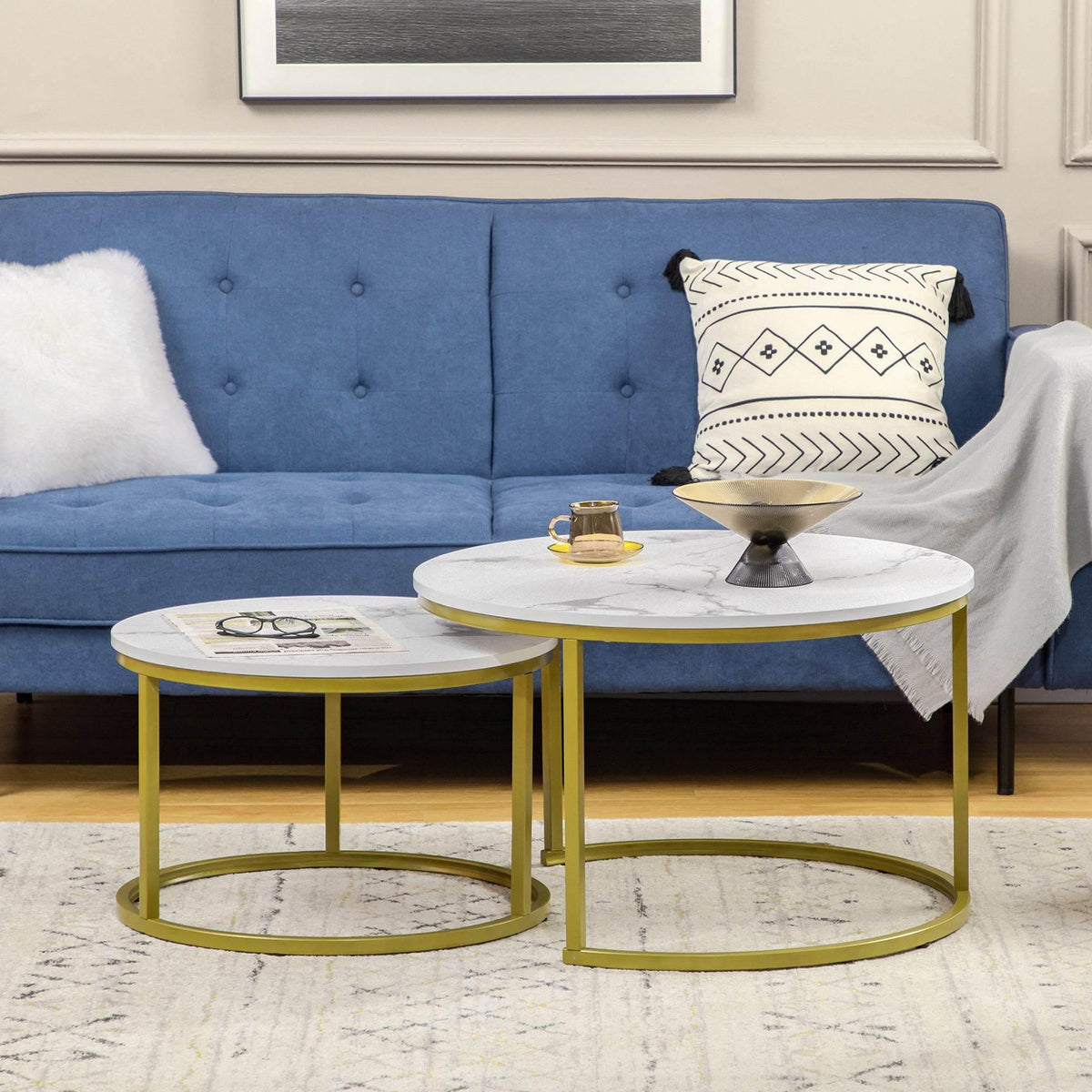 Two round nesting coffee tables with white faux marble tops and gold metal frames