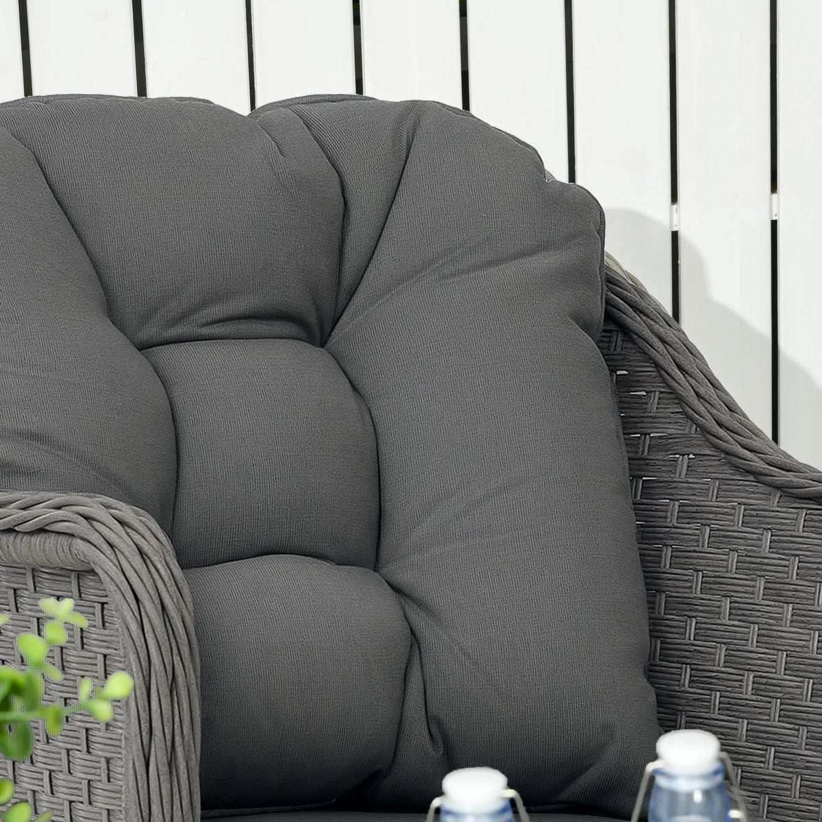 Dark gray tufted patio armchair back cushion and woven rattan frame close-up