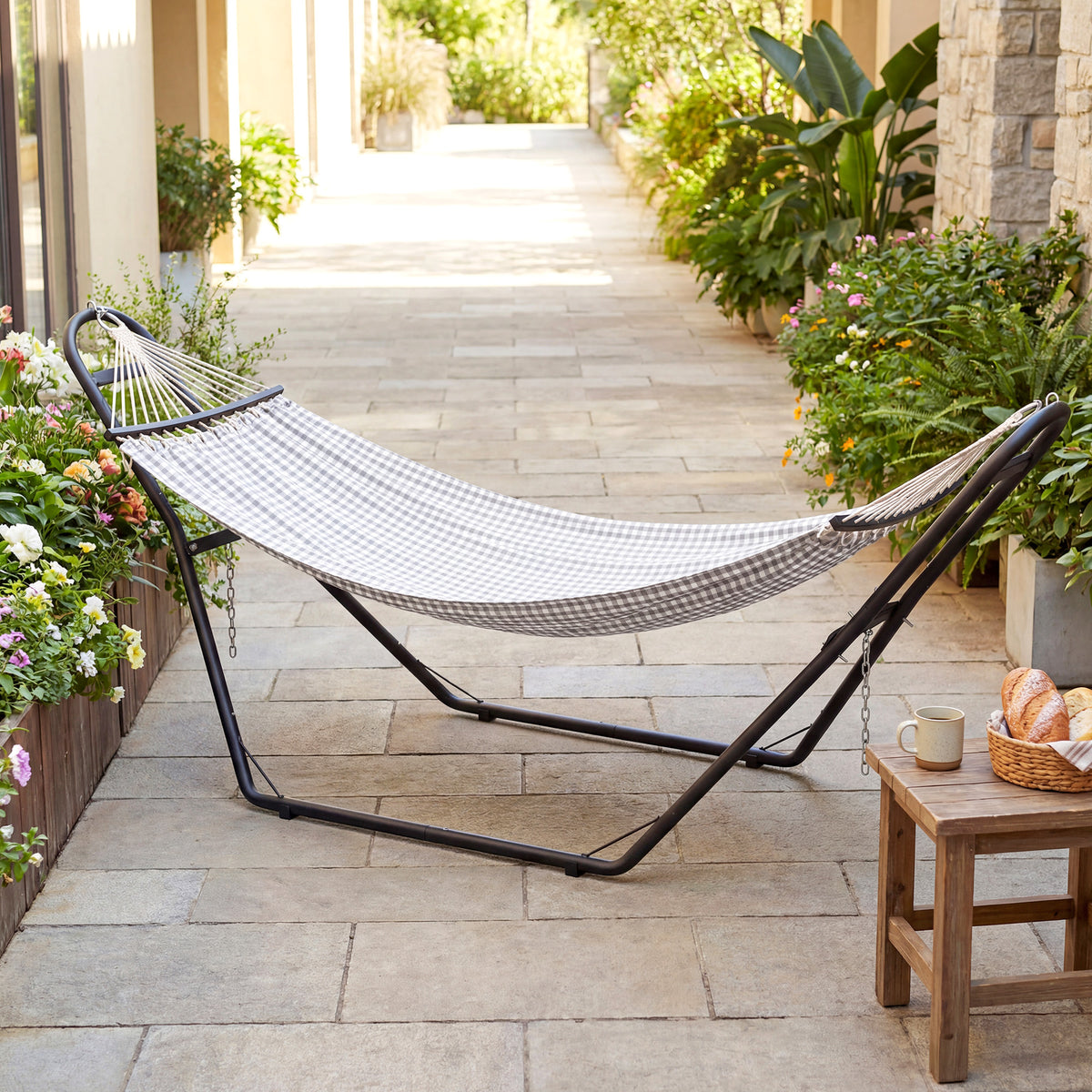 Black hammock stand with a white hammock stretched between the end posts