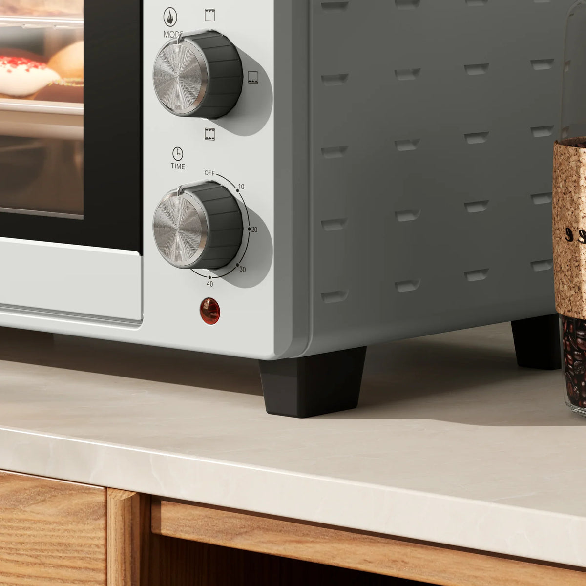Lower side of silver mini countertop oven with control knobs and vented metal panel