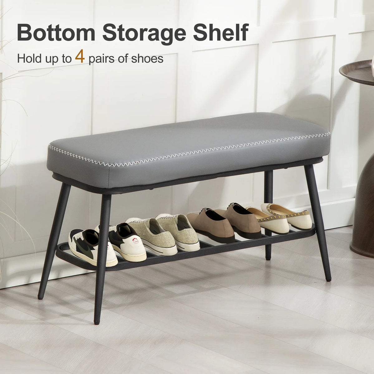 Grey PU leather shoe storage bench with cushioned seat and lower shelf holding shoes