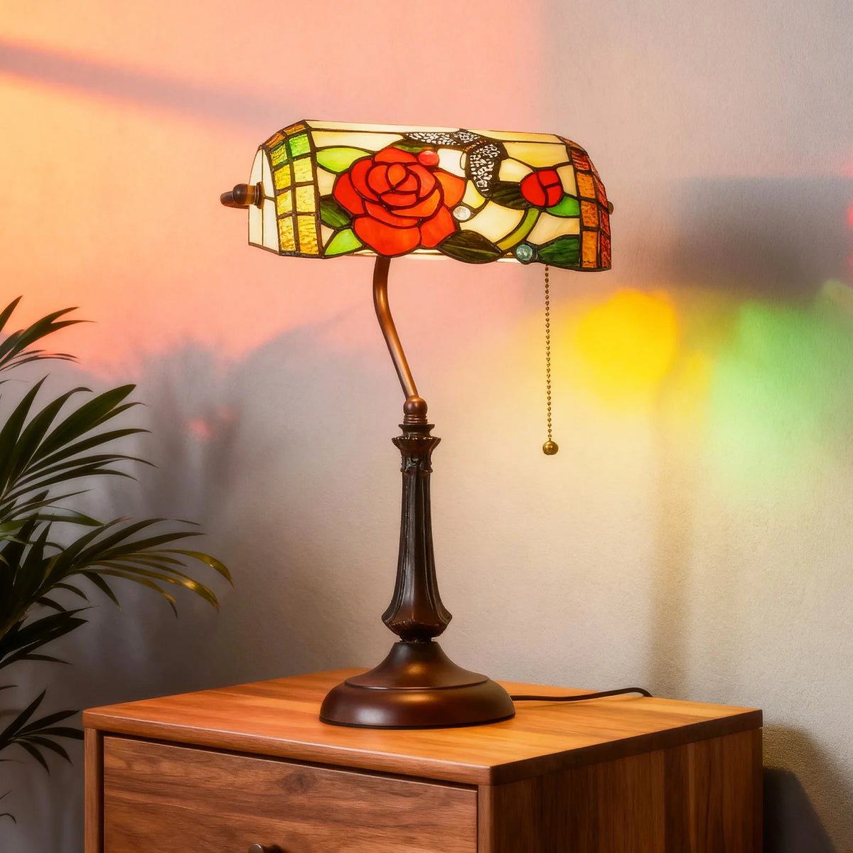 Front view of Tiffany-style stained-glass rose table lamp with bronze base and hanging chain