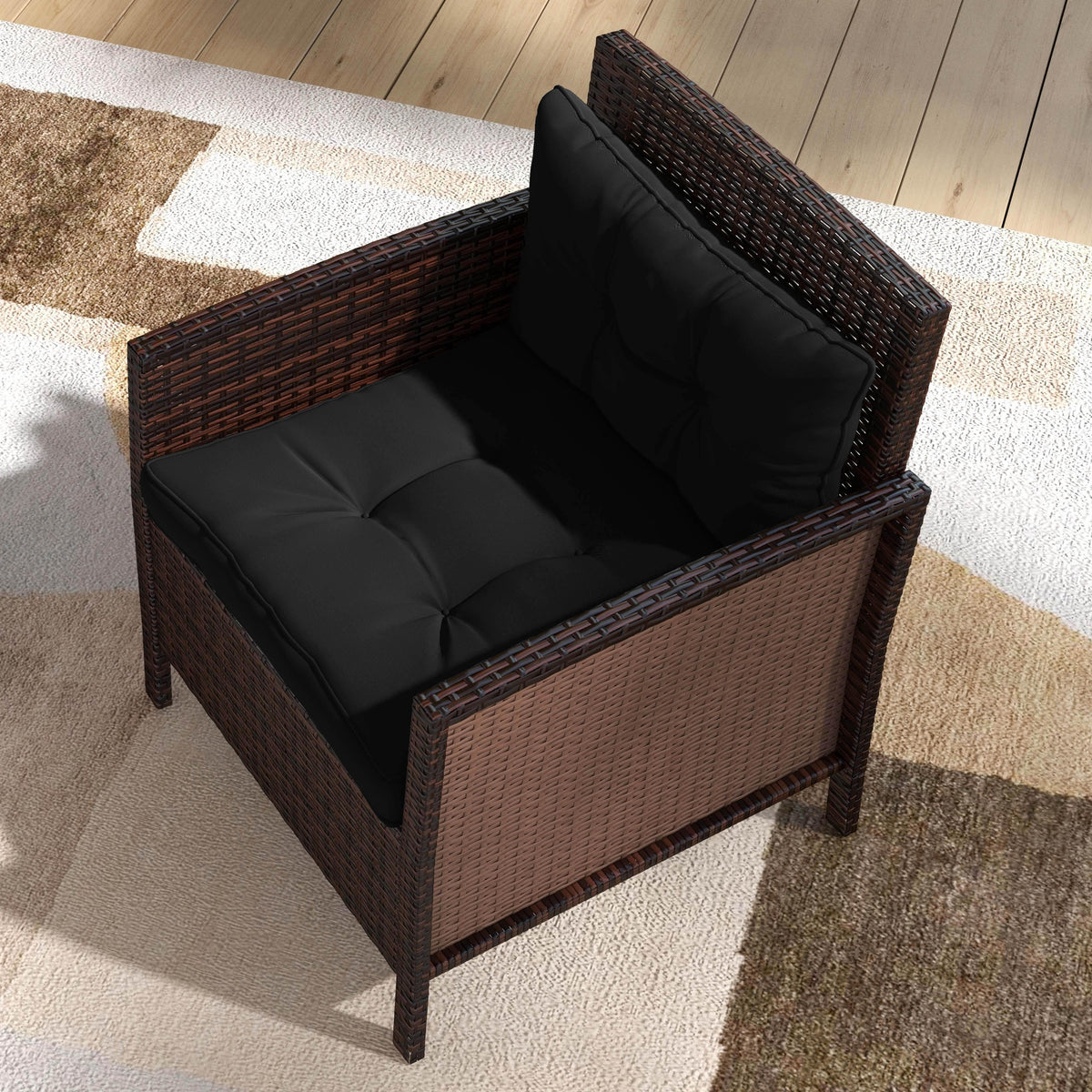 Patio armchair with dark brown wicker frame and black padded seat and back cushions