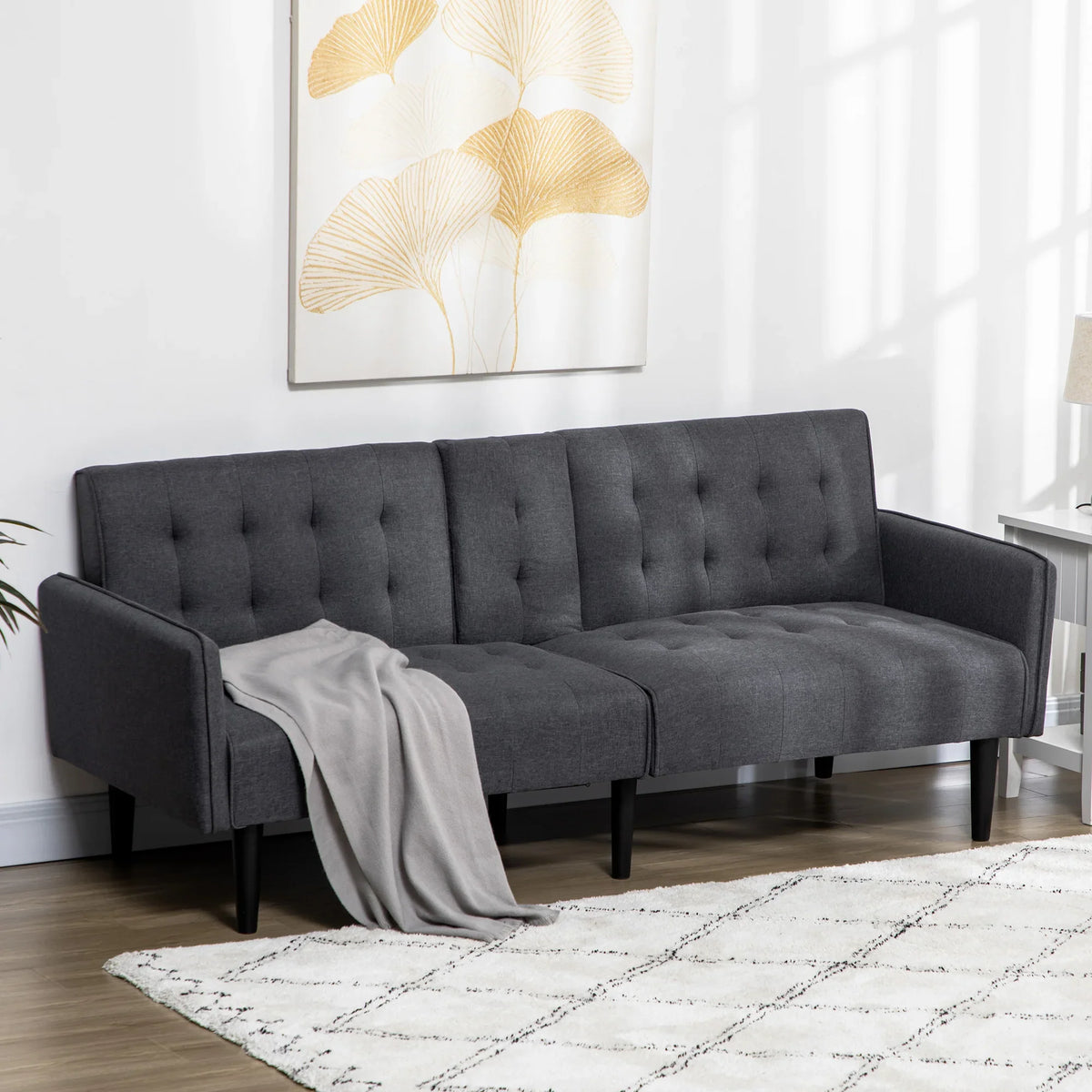 Grey three-seat convertible sofa bed with tufted backrest and curved armrests