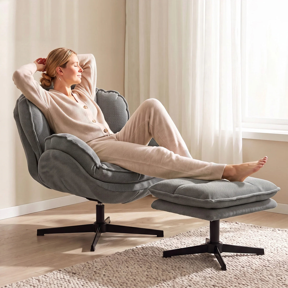 Grey swivel armchair with adjustable footstool and thick cushioning; woman relaxing