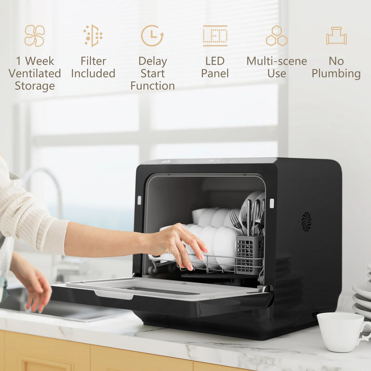 Black countertop dishwasher with open door and hand loading white dishes