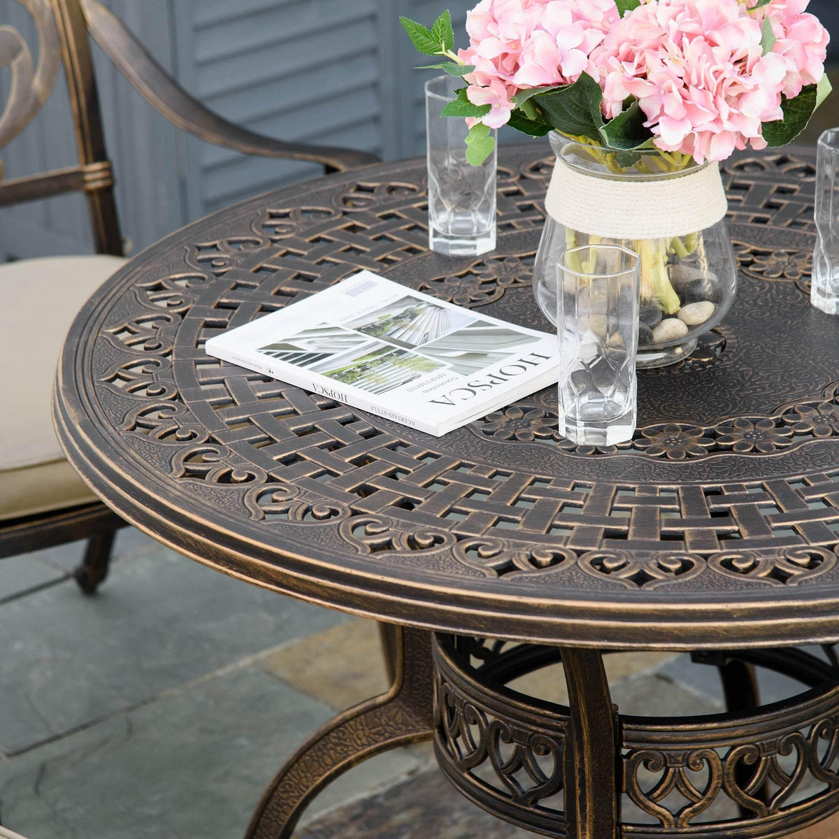 Bronze outdoor dining table with ornate lattice top and beige-cushioned chairs