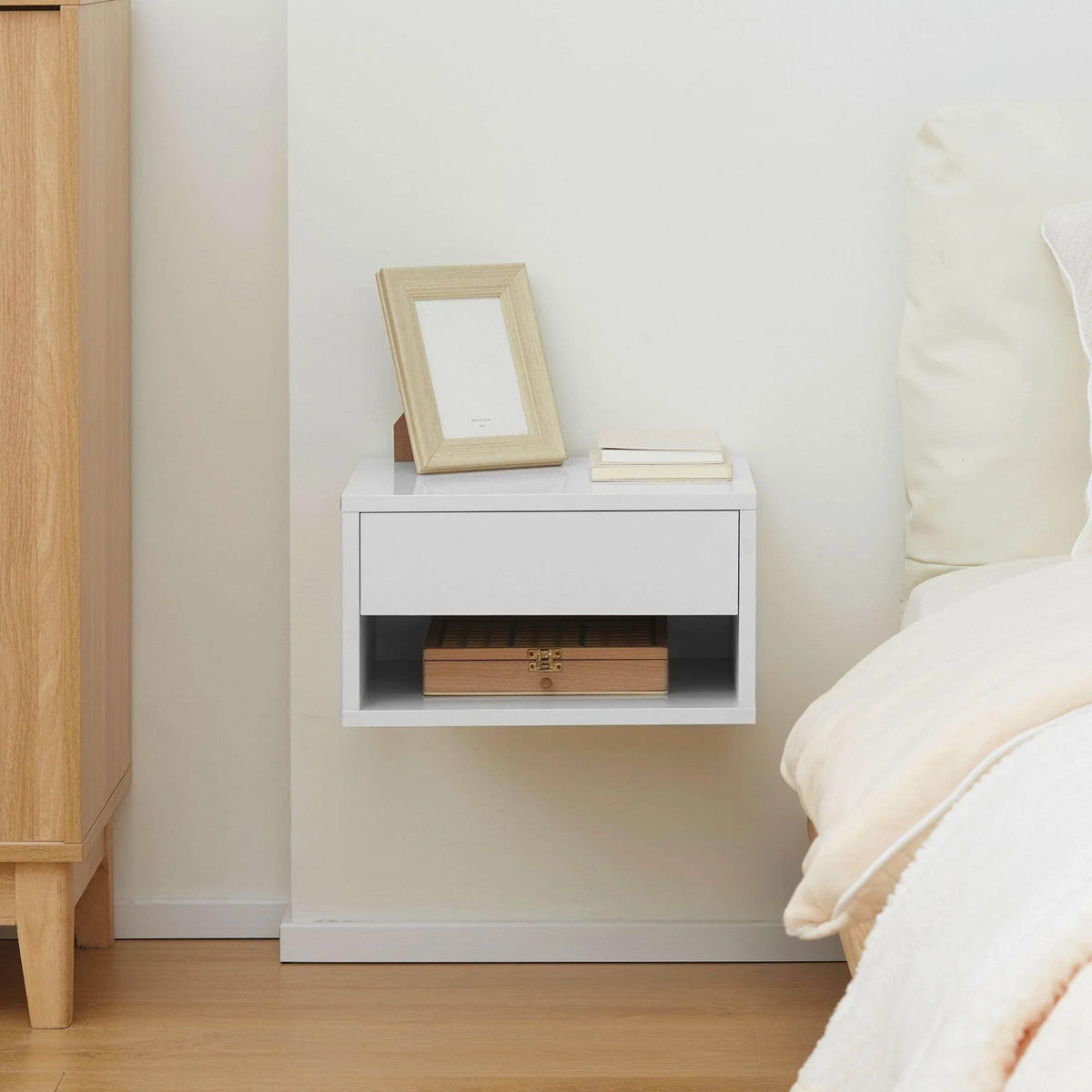 White wall-mounted nightstand with open shelf and drawer beneath picture frame