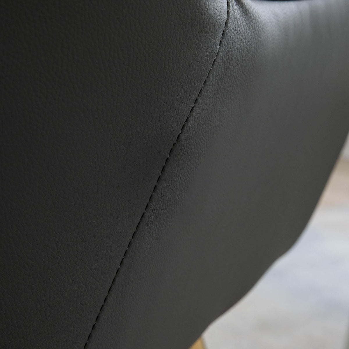 Grey upholstered armchair side panel with visible seam and smooth texture