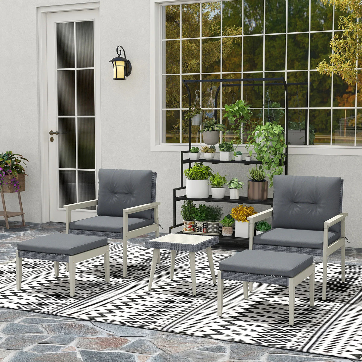 Grey rattan patio conversation set with two armchairs, ottomans, and small table