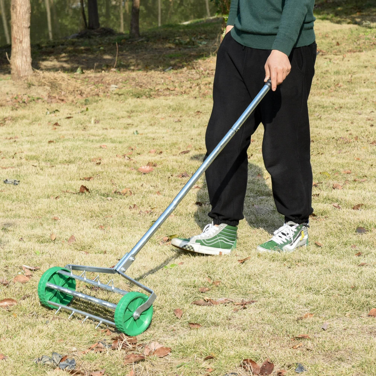 Rolling lawn soil aerator with green spike drum and adjustable silver handle