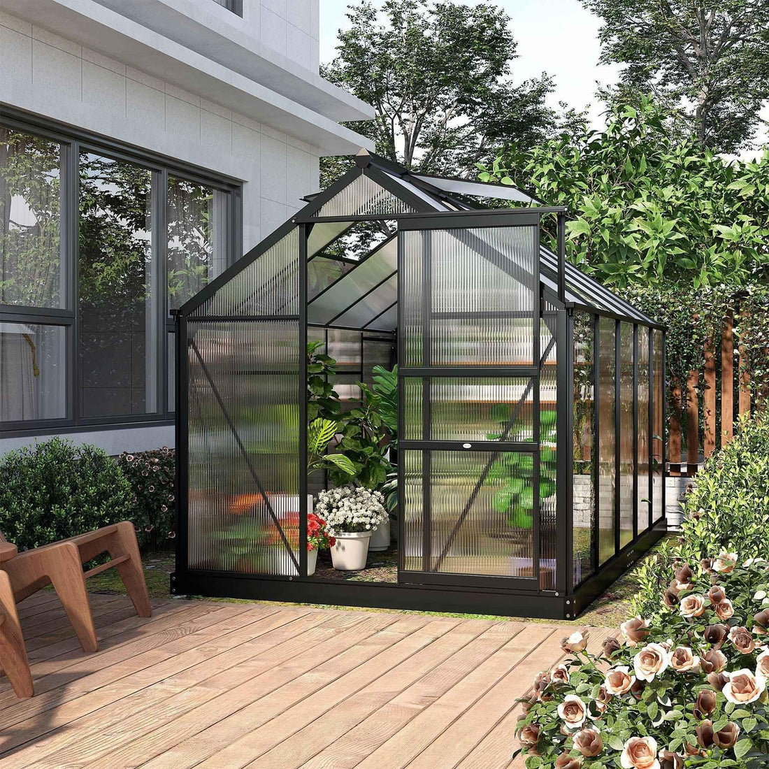 Black metal greenhouse with clear panels on wooden deck, perfect for home garden plants and flowers.