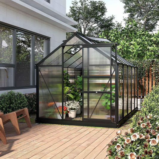 Black metal greenhouse with clear panels on wooden deck, perfect for home garden plants and flowers.