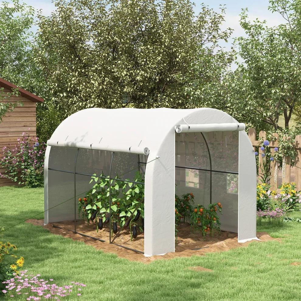 White garden greenhouse with plants inside, set in a lush backyard with flowers and trees