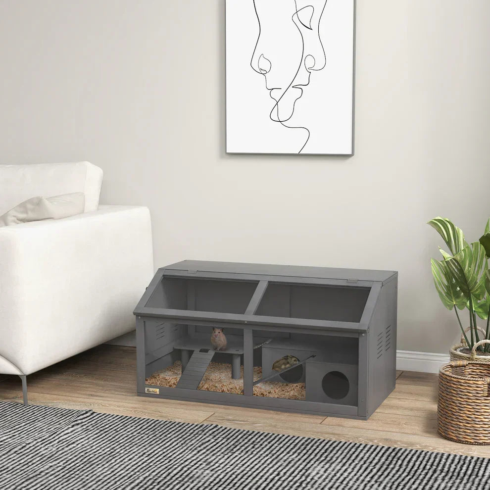 Gray hamster cage with multiple levels, ramps, and bedding in a cozy living room setting