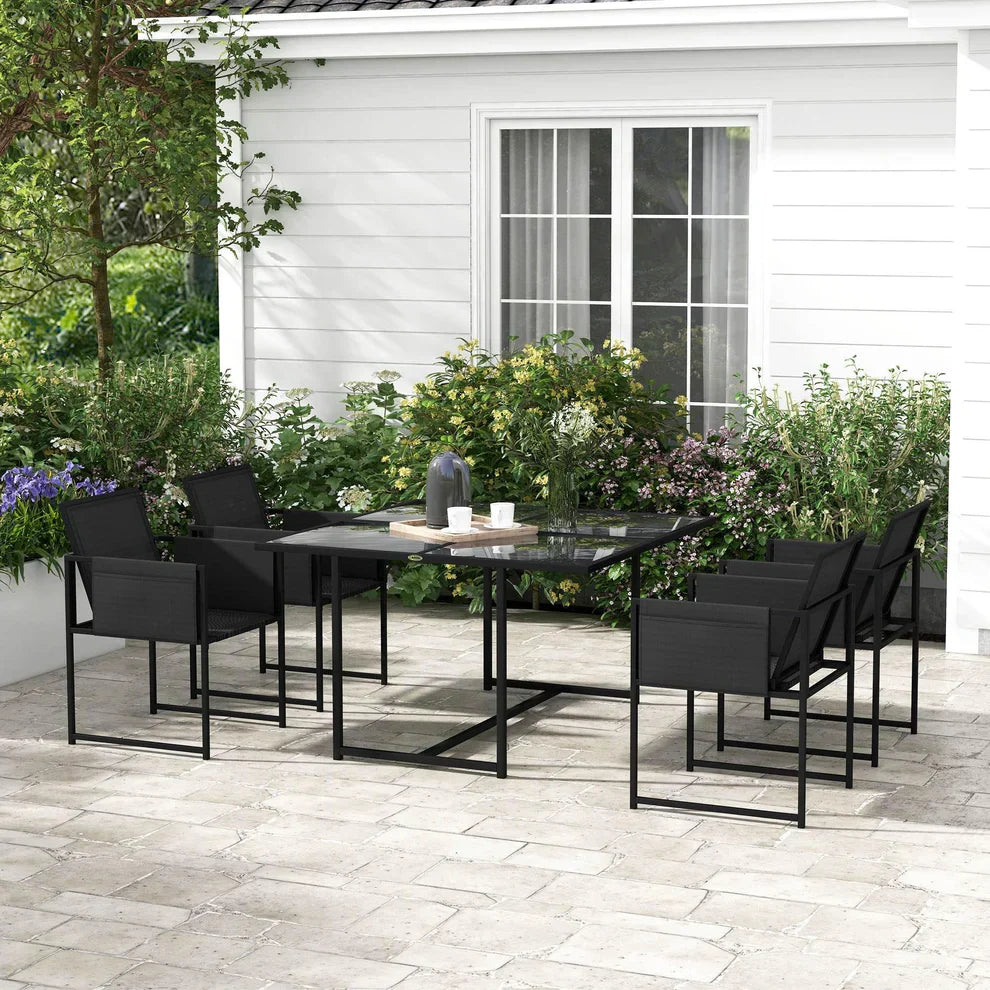 Modern black patio dining set with glass table and six chairs on a stone terrace, garden view