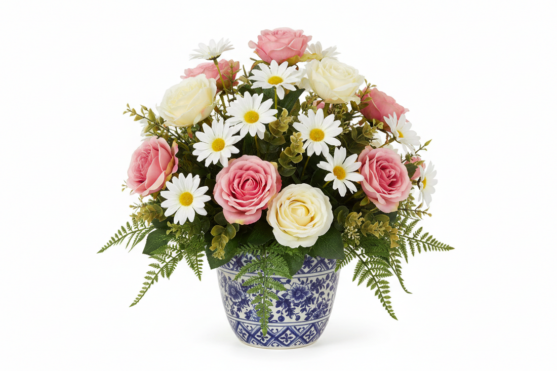 Artificial flower arrangement with pink roses and white daisies in a blue patterned pot
