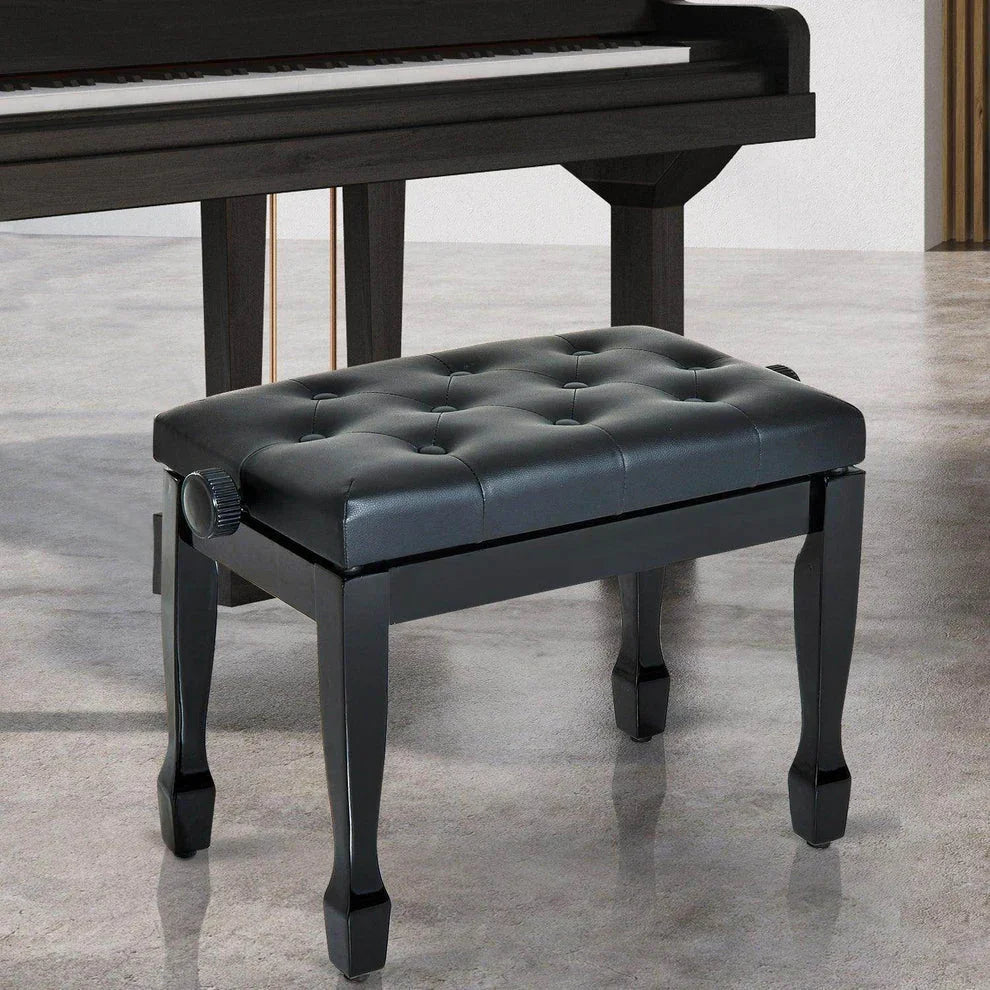 Black tufted piano bench with adjustable height, sleek legs, positioned beside grand piano in modern room