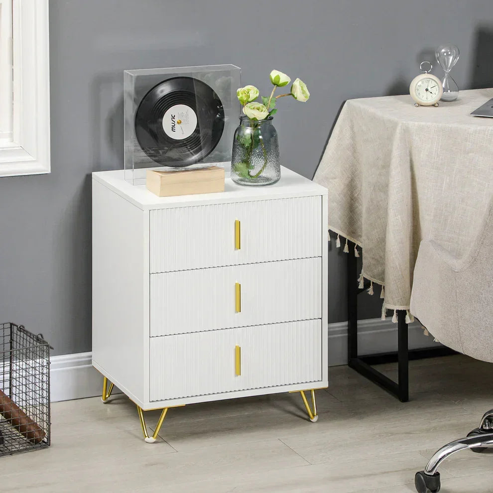 White 3-drawer nightstand with gold handles and legs, styled with vinyl record and flowers in modern home setting