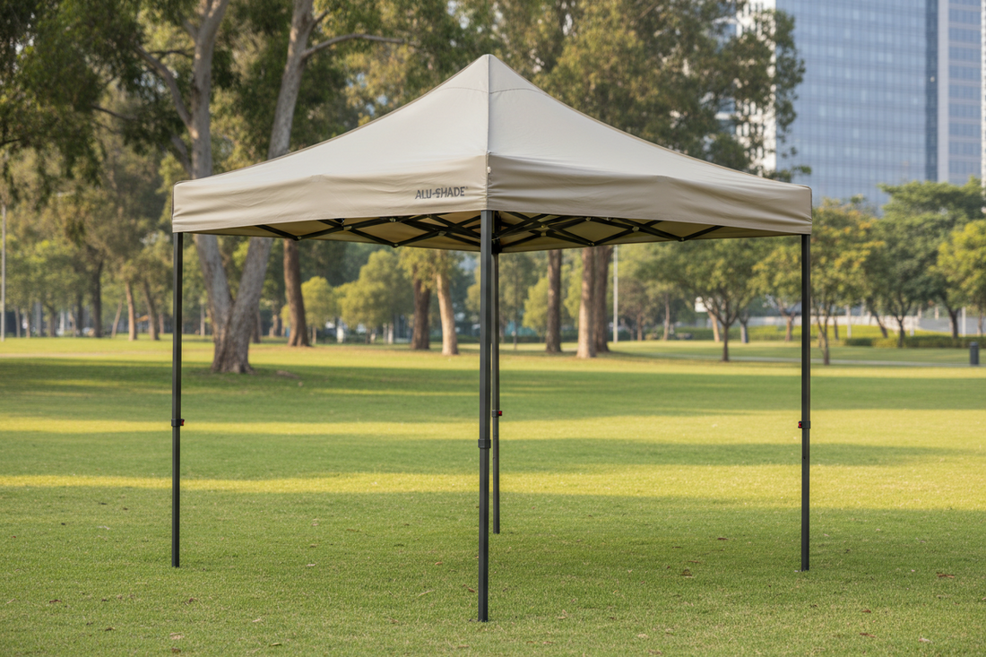 Pop-up gazebo with beige canopy set up on green grass in a park, outdoor shelter tent