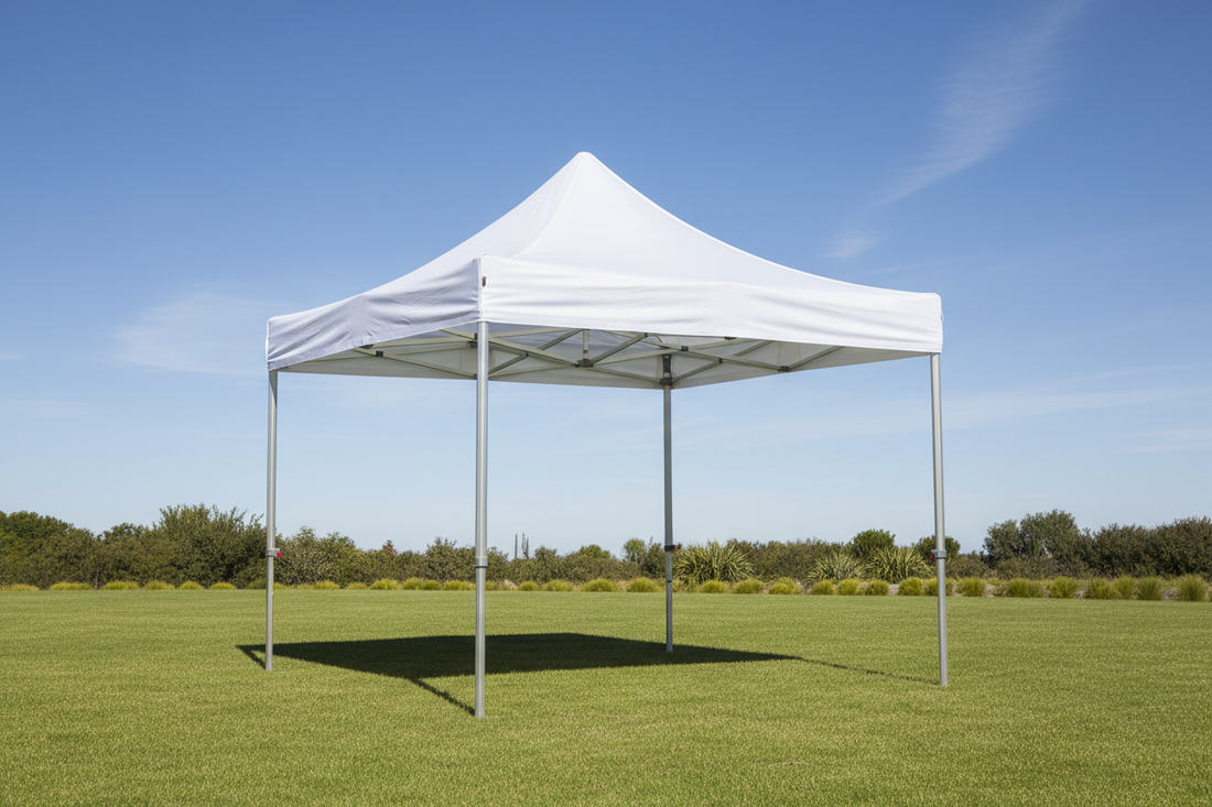 White pop-up gazebo tent on green grass outdoors with clear blue sky