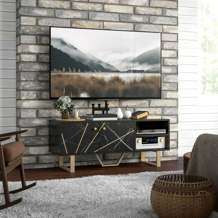 Modern black marble TV stand with gold accents, styled in cozy living room with stone wall and rug