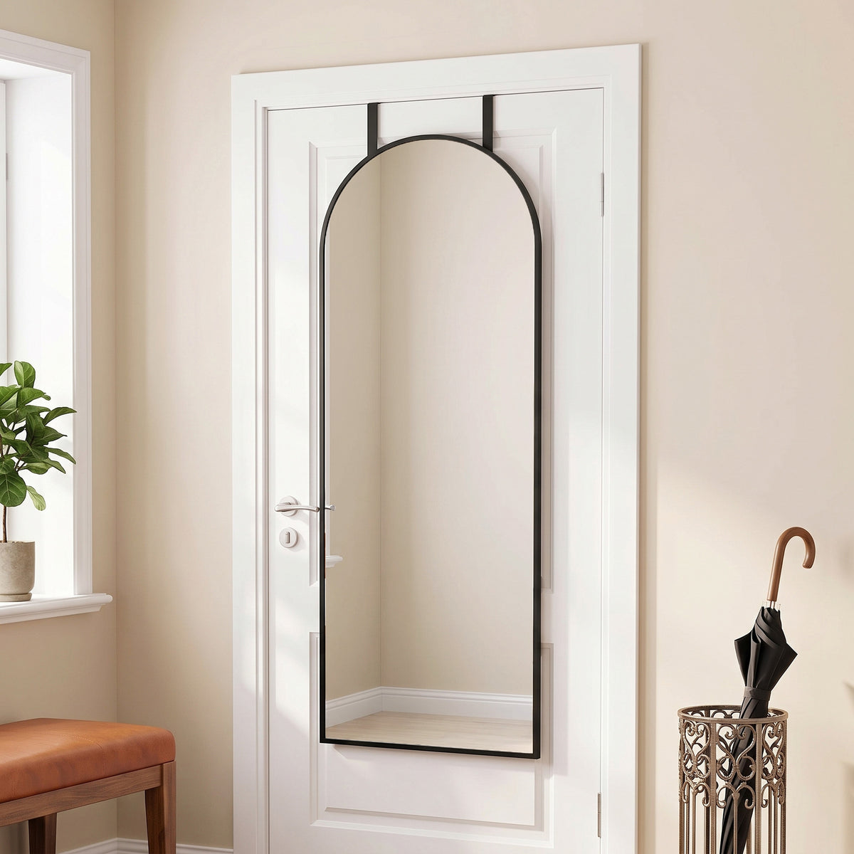 Arched full-length wall mirror with black frame and hanging hooks on a door