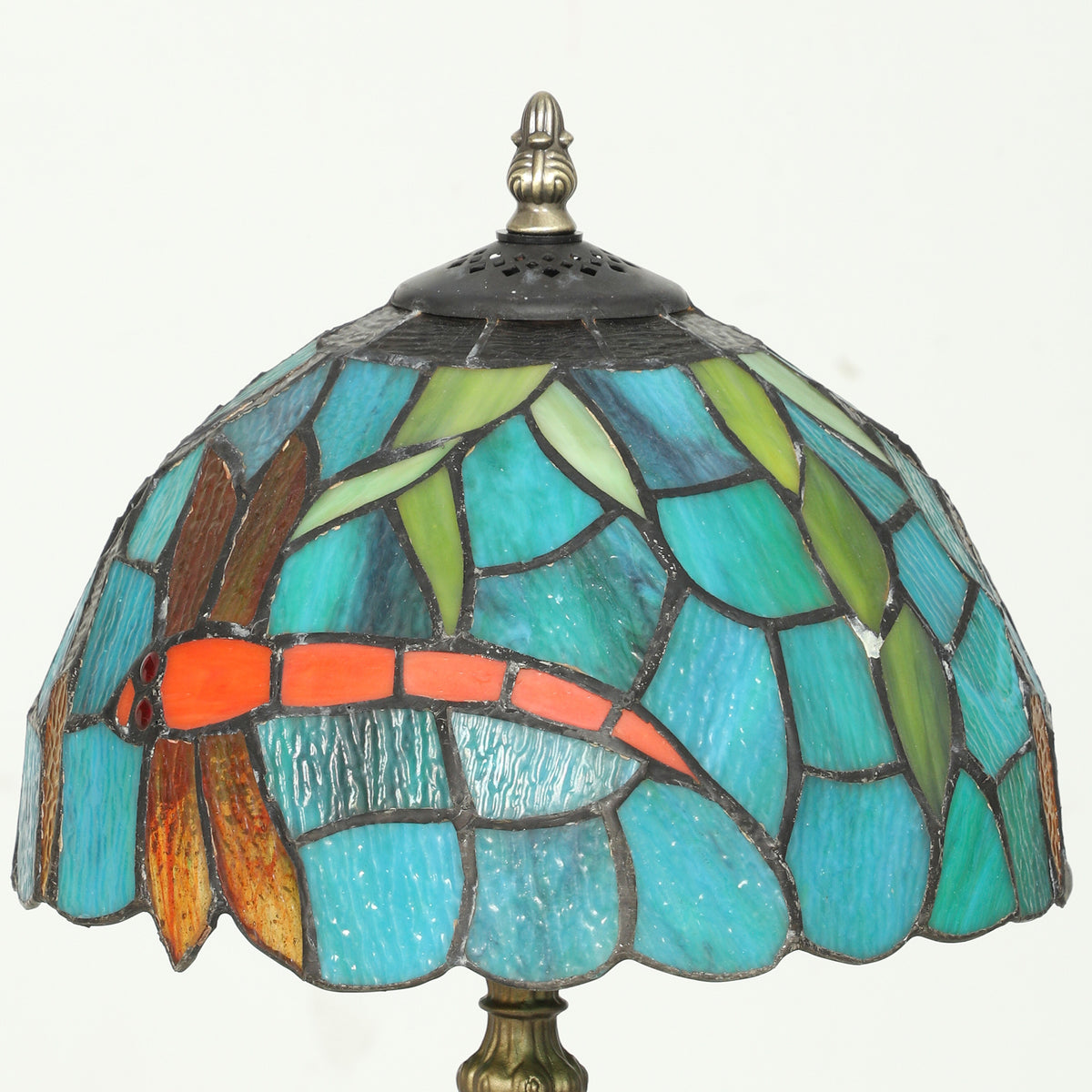 Green-blue stained glass lamp shade with brass finial and scalloped edge.