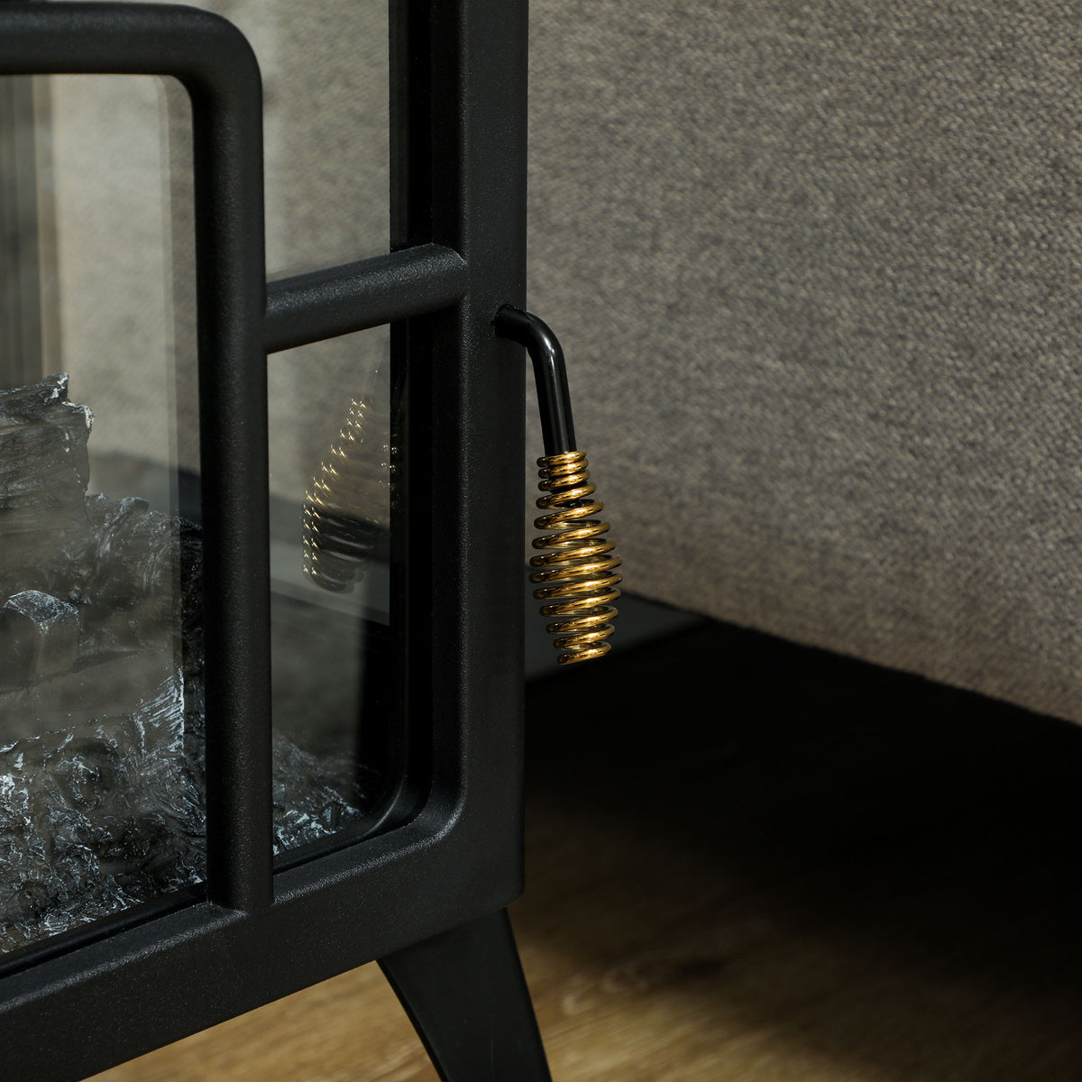 Close-up of black electric fireplace stove side handle and framed glass panel