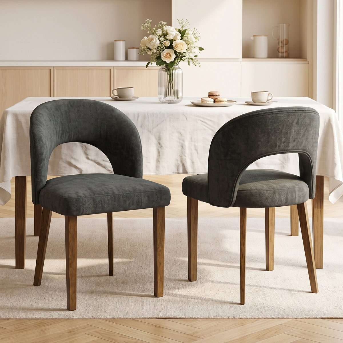 Front view of two dark grey upholstered dining chairs with curved arched backs and legs