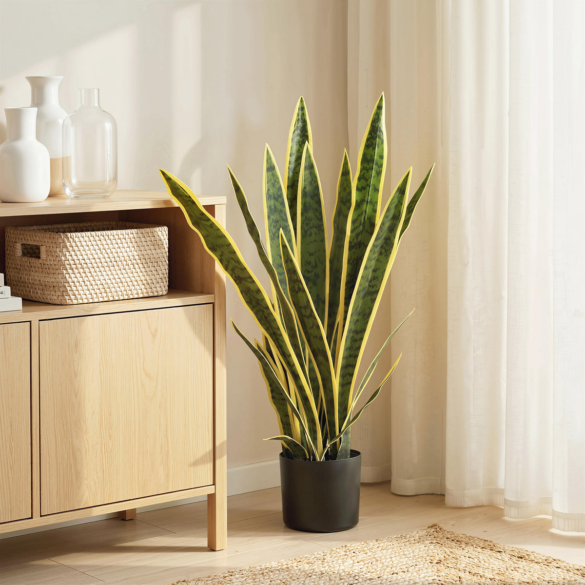 Artificial snake plant with variegated upright leaves in black pot