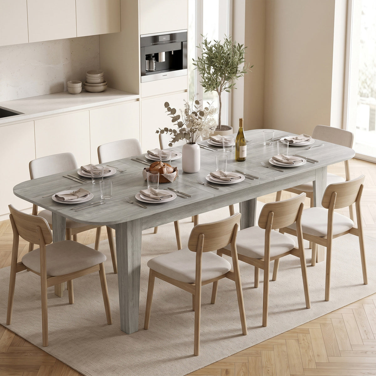 Grey wood-effect extendable oval dining table set for dining with chairs in a room.