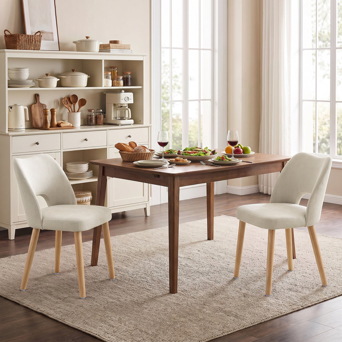 Set of 2 beige upholstered dining chairs with rounded backs and light wood legs.