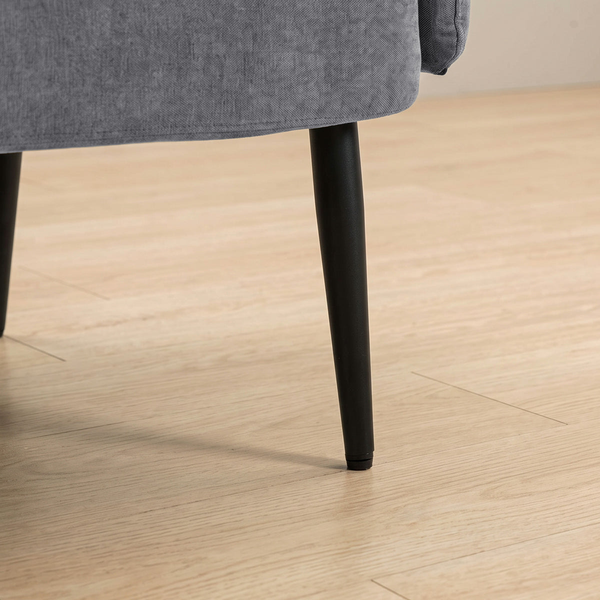 Close-up of dark tapered legs under a light grey velvet sofa
