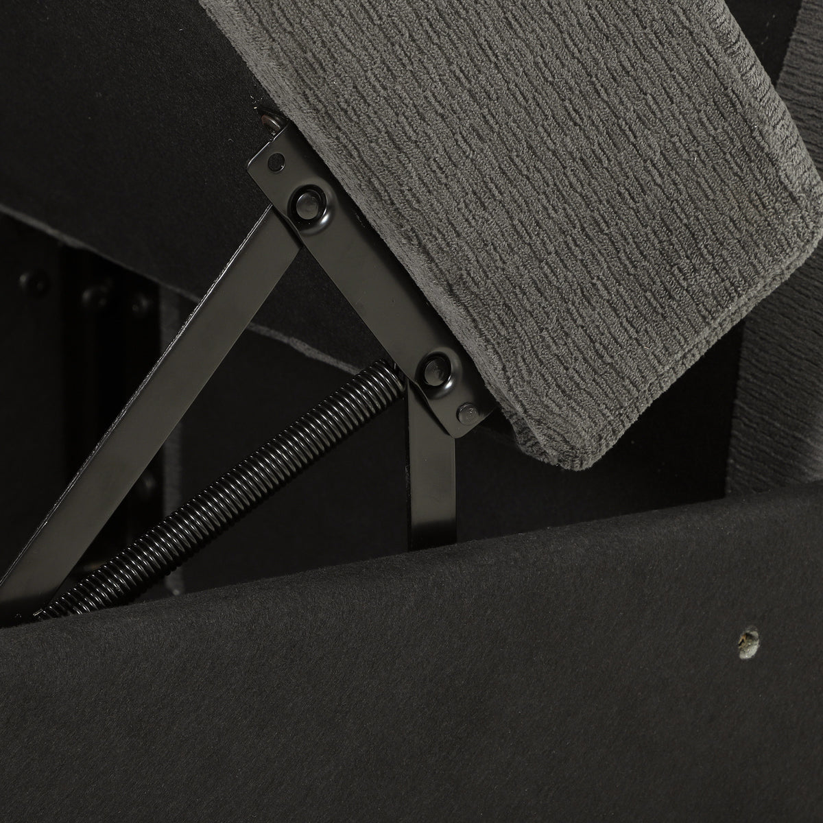 Lift-up storage mechanism on dark grey sofa seat, showing hinges and springs
