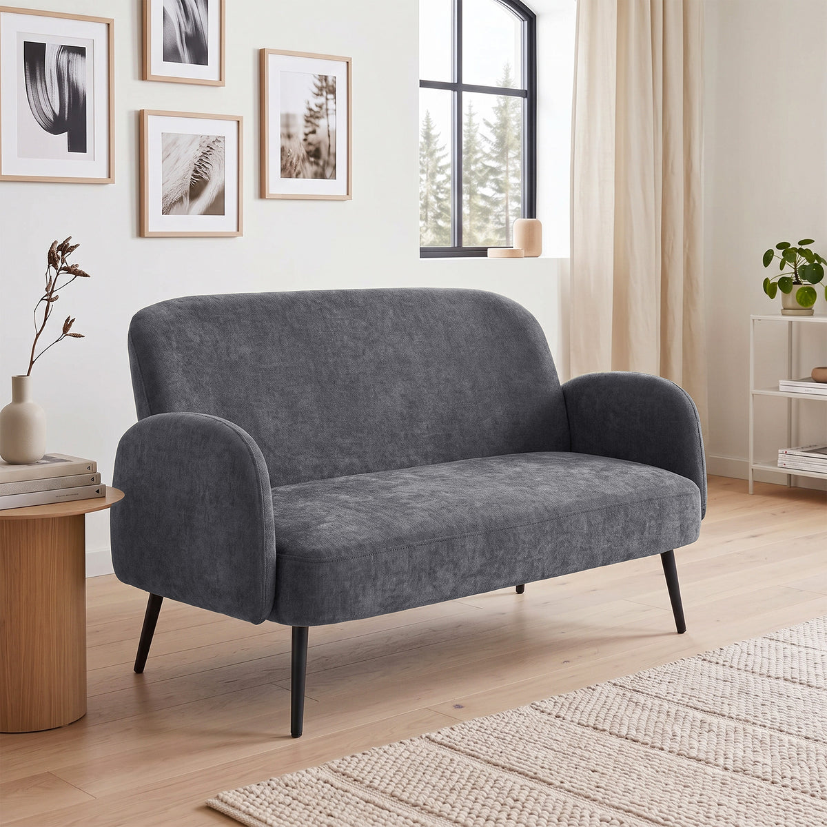 Dark grey velvet loveseat with curved arms and tapered metal legs