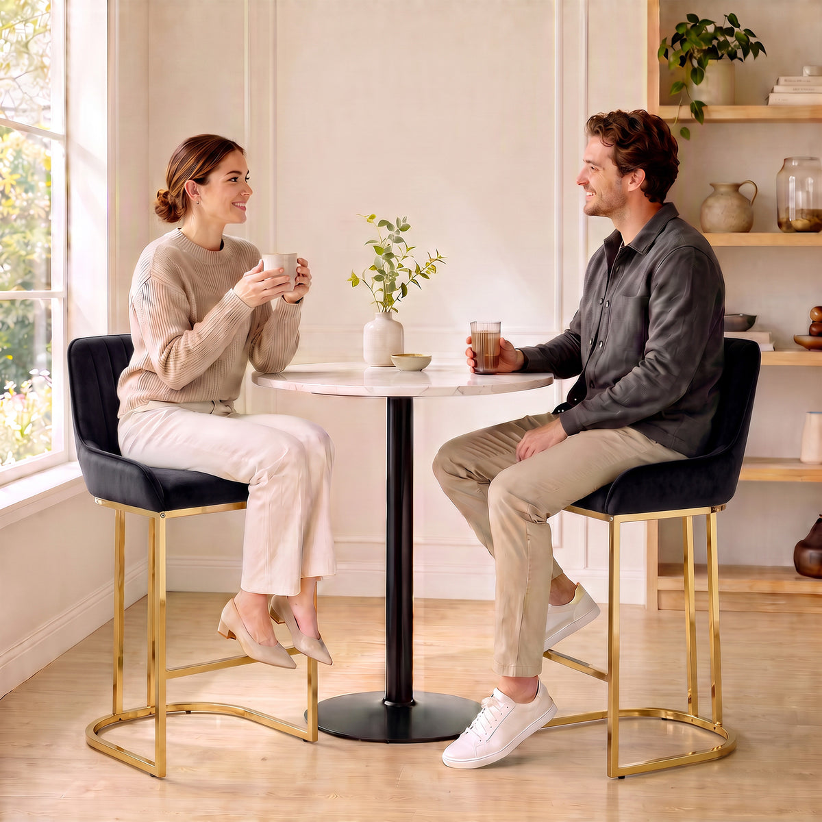 Two black velvet bar stools with gold frames and footrests, styled in a kitchen setting