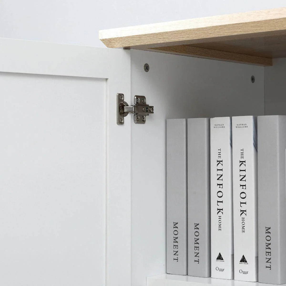 Close-up of white cabinet door hinges and interior shelves with stored books
