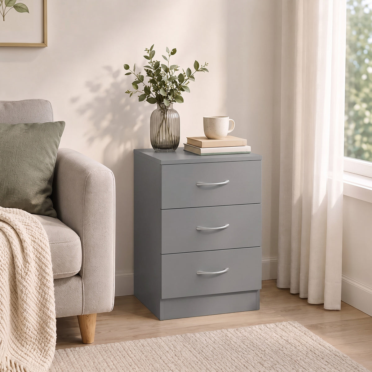 Grey three-drawer nightstand with curved silver handles and open shelf top.