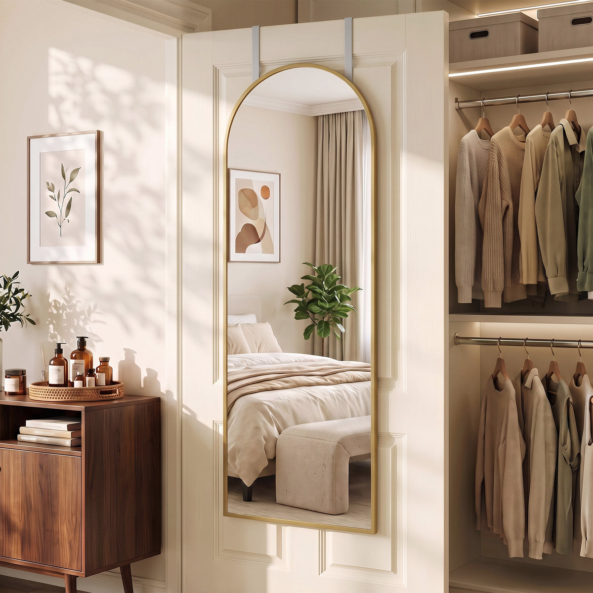 Gold-framed arched mirror hanging on door, reflecting bedroom and closet