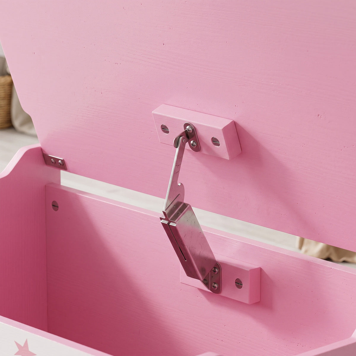 Close-up of pink flip-top lid hinge mechanism on wooden toy chest