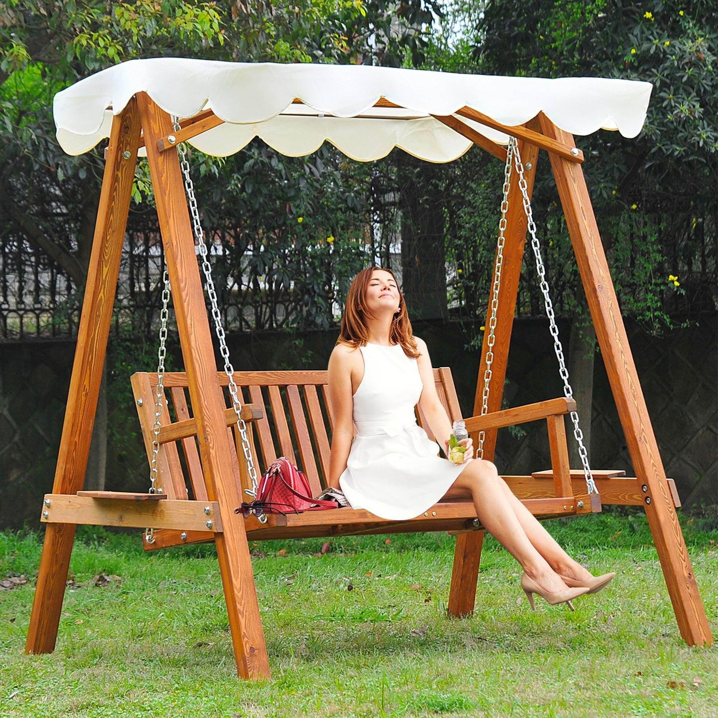 Wooden 2 seater garden swing with cream canopy, woman relaxing on bench, outdoor setting