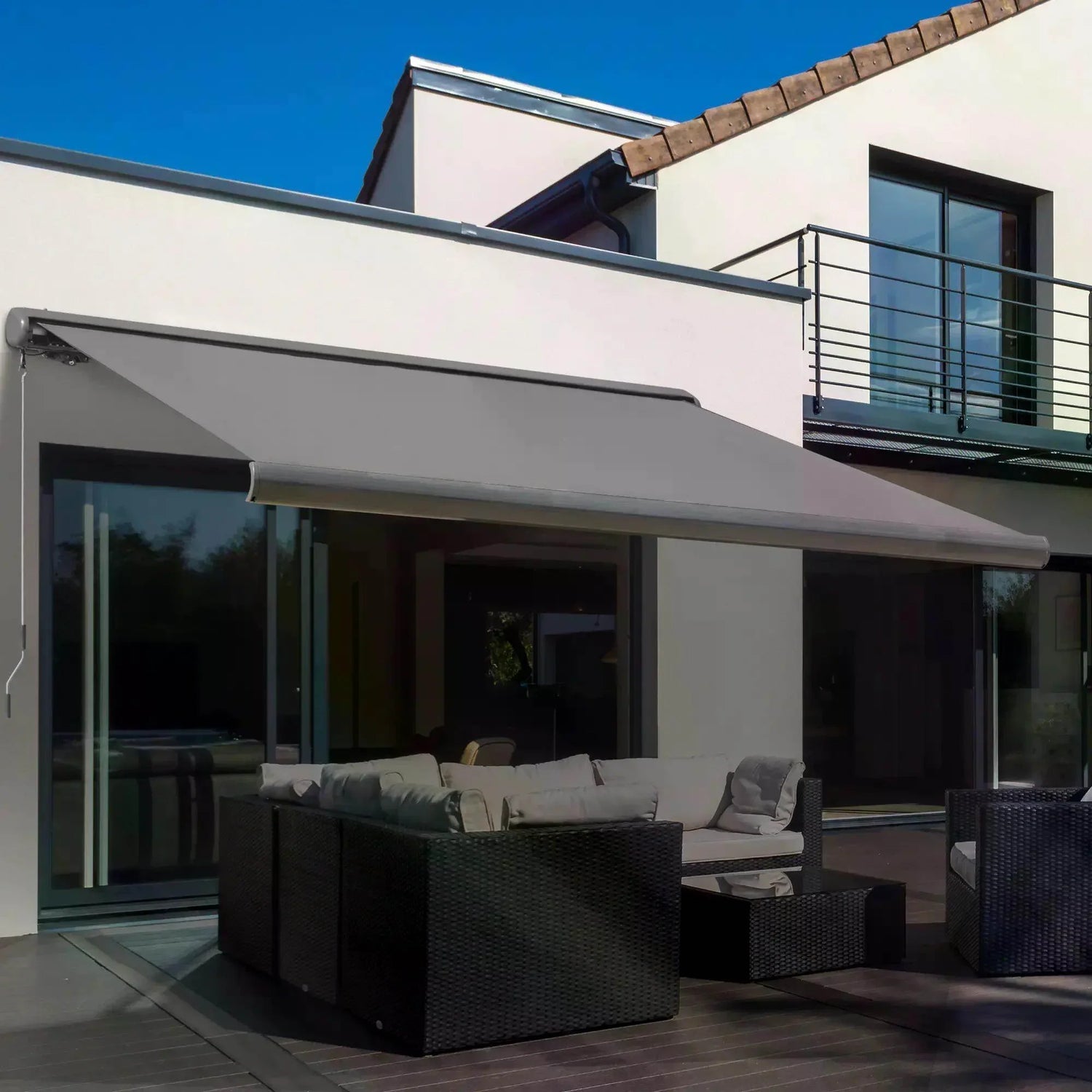 Grey motorized cassette awning installed with dark grey shade over an outdoor seating area